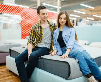 Couple sitting on a bed asking if putting a mattress directly on a bed frame is a good idea.