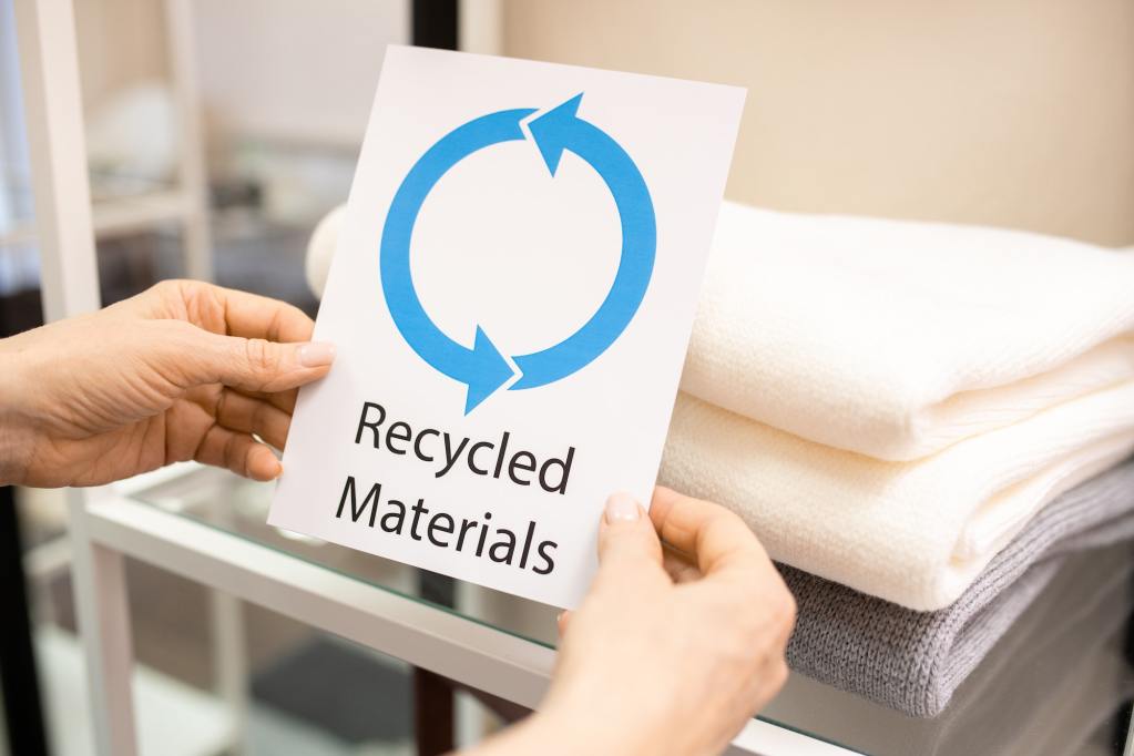 Holding a sign that says recycled materials. Dispose Of Packing Materials.
