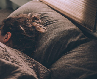 Woman sleeping on her side under covers in bed