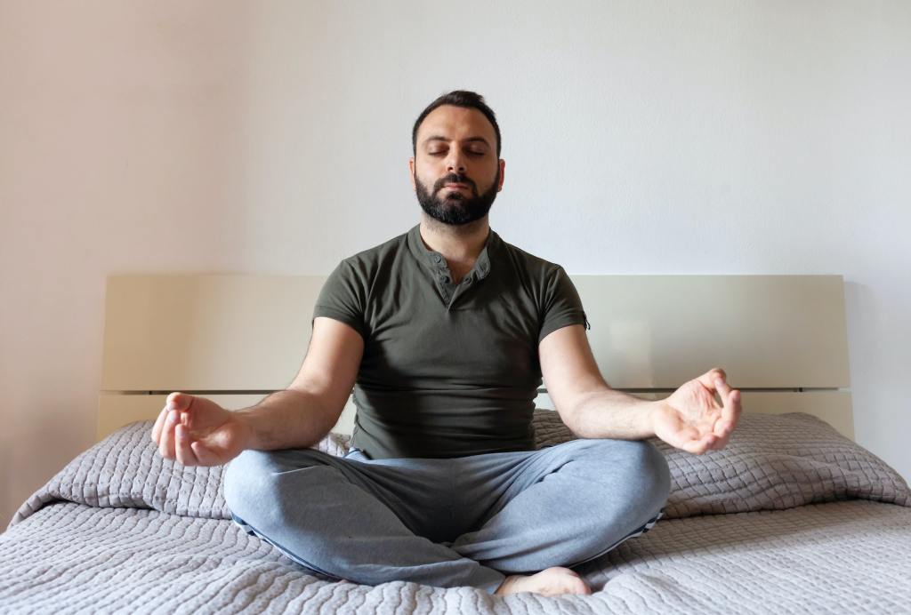 Man relaxing with yoga in his bedroom. He has taken care of important details to pay attention to in the bedroom for this comfort.