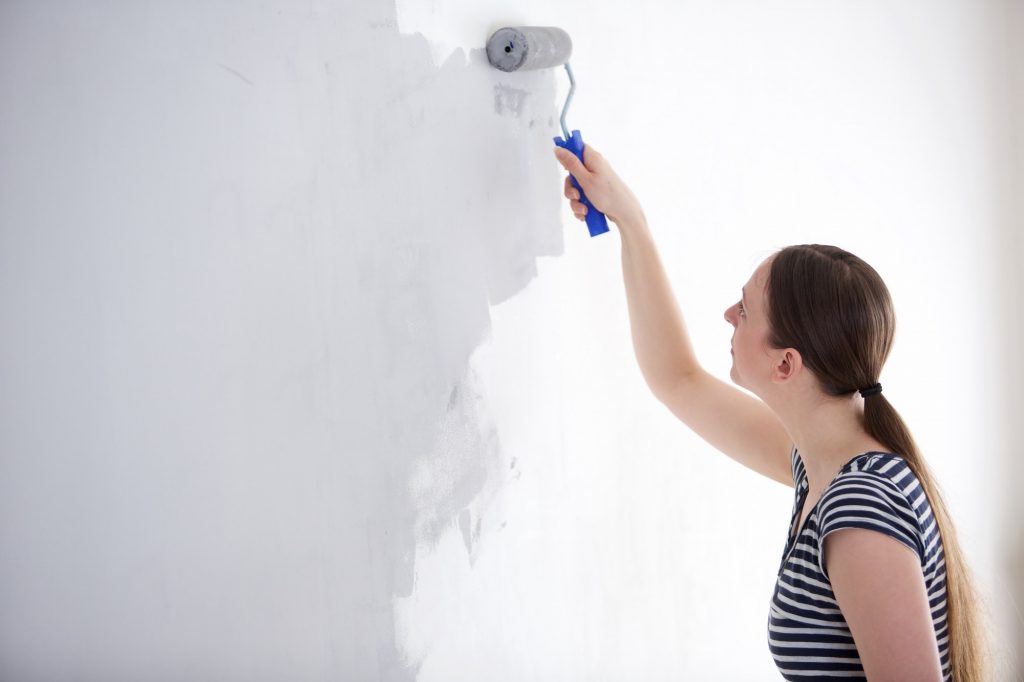 Young woman painting wall of her home.